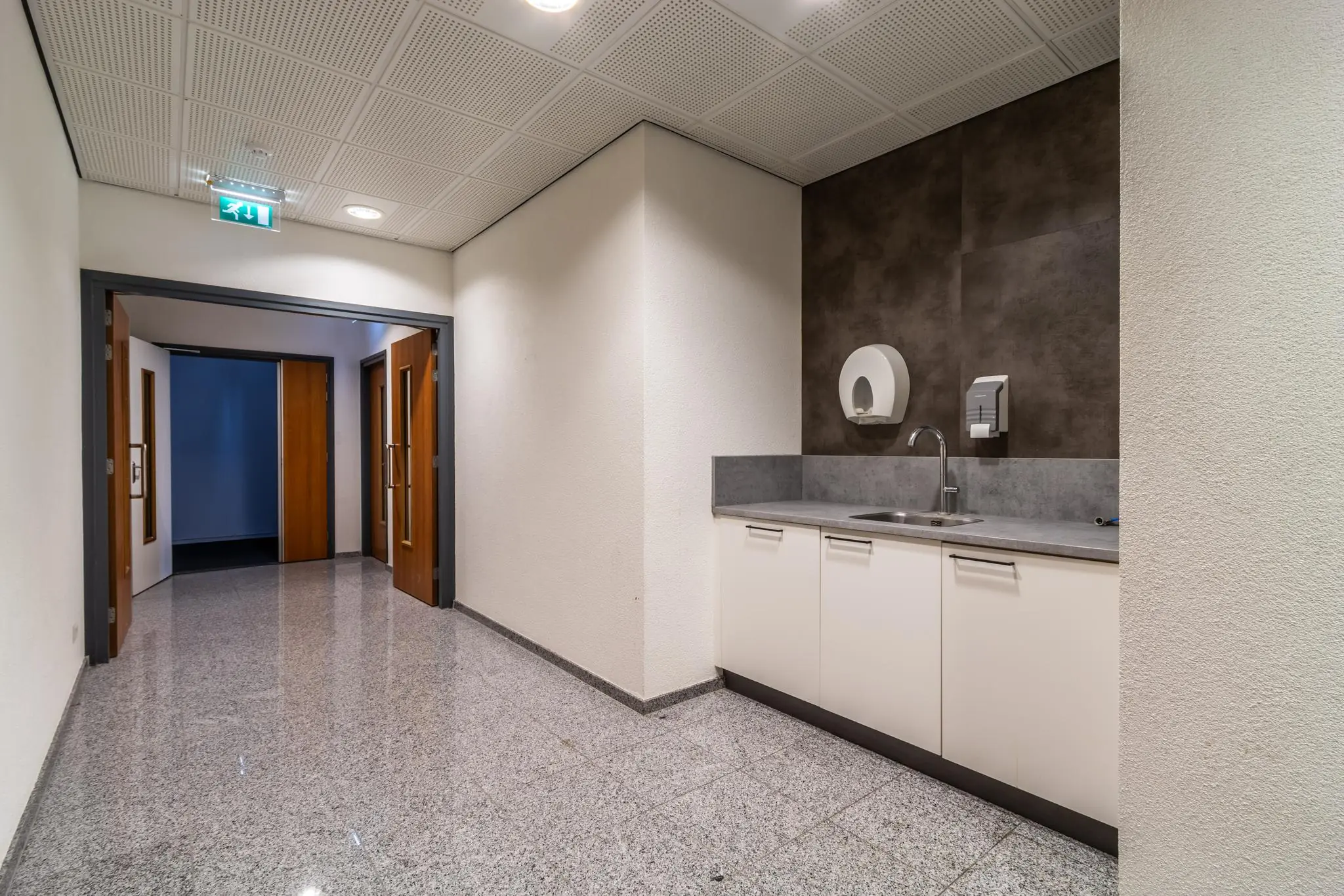 Keukenblok met wasbak en zeepautomaat in een gang van een kantoorpand aan de Lange Dreef.